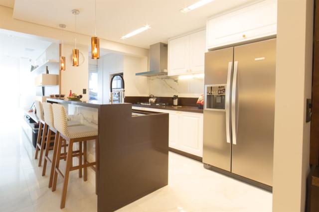 Cozinha com ilha e banquetas integrada à sala em apartamento reformado em São Paulo